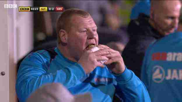 Il secondo portiere del Sutton United Wayne Shaw preferisce mangiarsi un panino. 